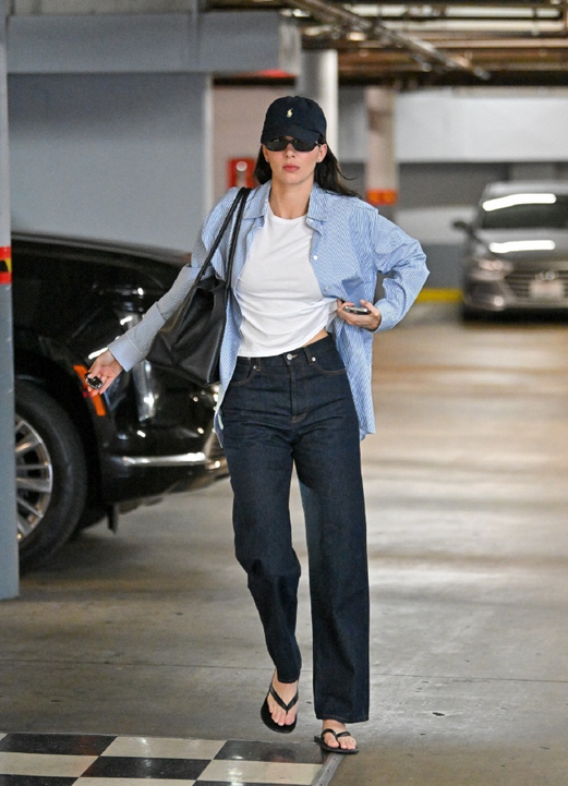 Kendall Jenner is wearing a long-sleeve shirt and jeans in a parking lot.
