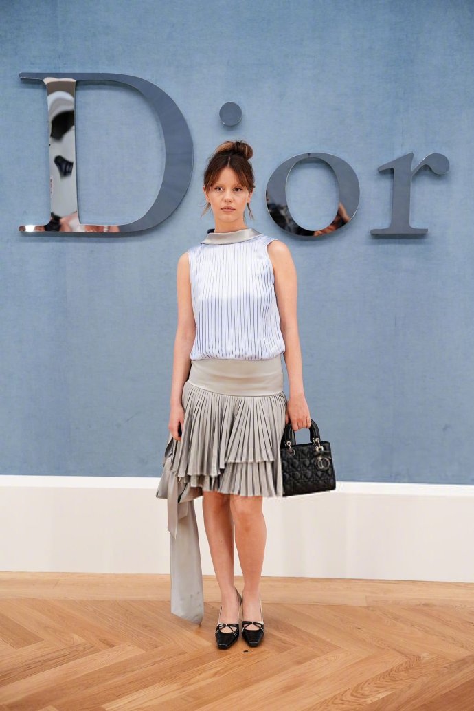 Mia Goth in sleeveless top & pleated skirt
