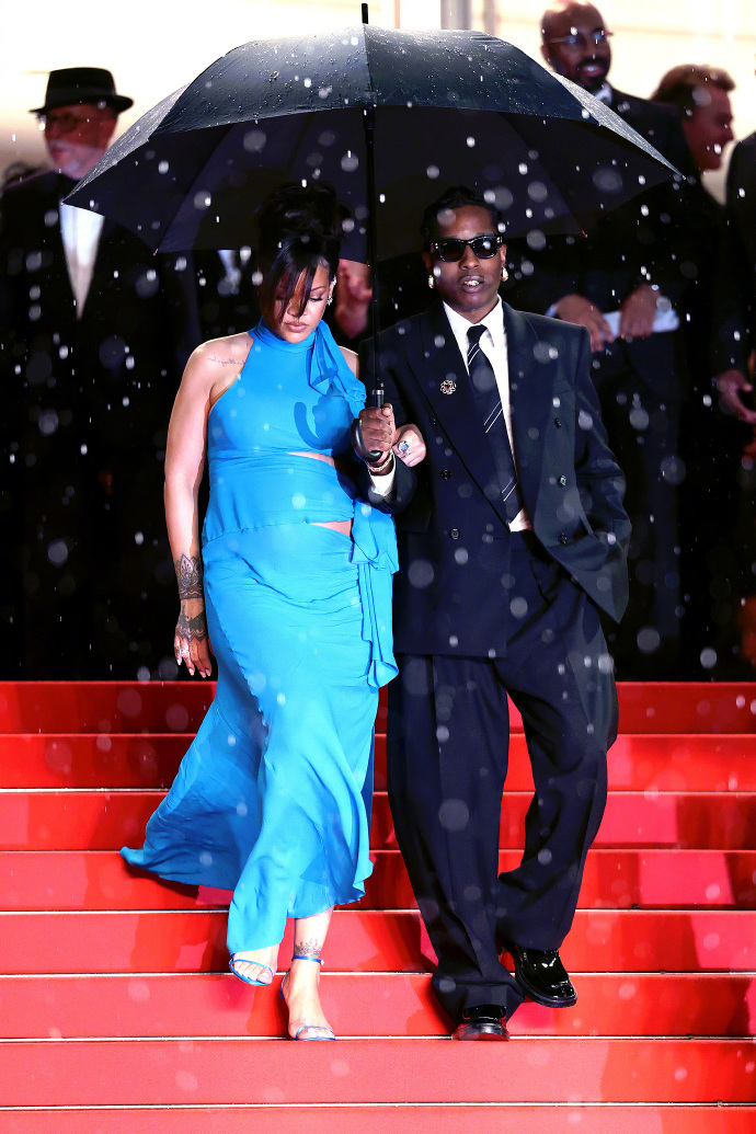 Pregnant Rihanna, dressed in a blue gown and holding an umbrella, leaves the Cannes venue.