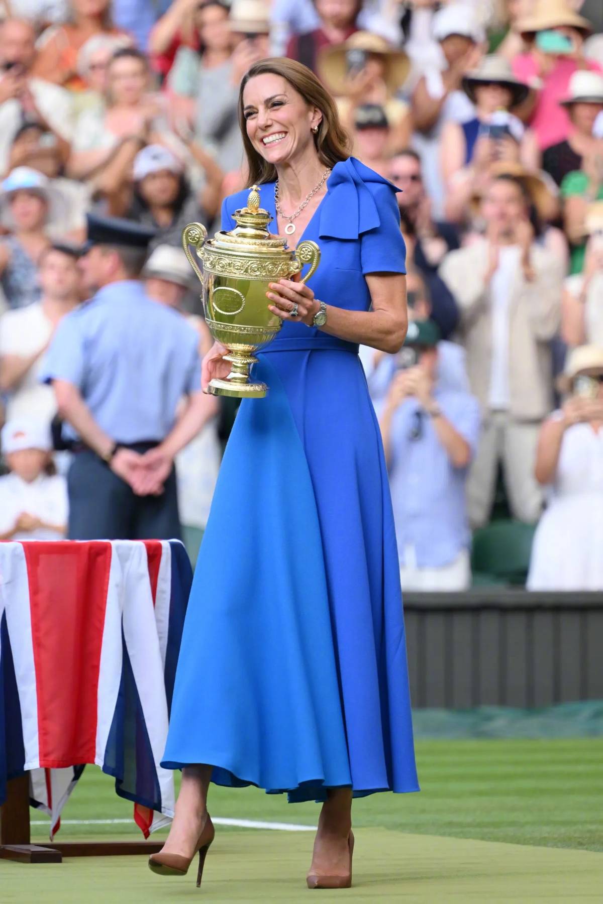 Princess Kate presents the trophy to the Wimbledon champion, wearing a vibrant blue dress