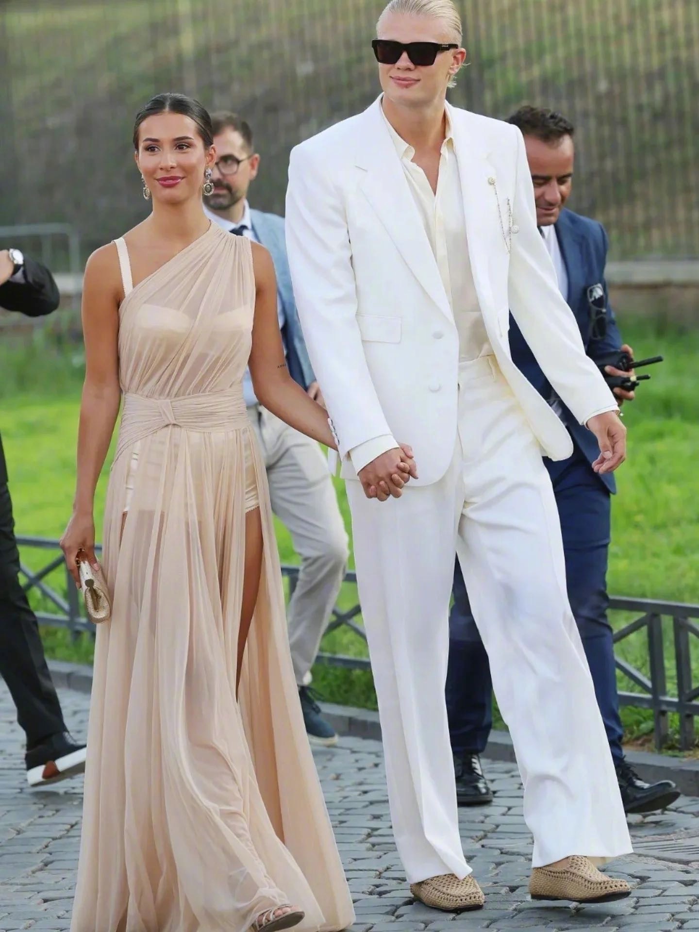 Erling Haaland (white suit) and his girlfriend (sheer one-shoulder gown) show off their outfits
