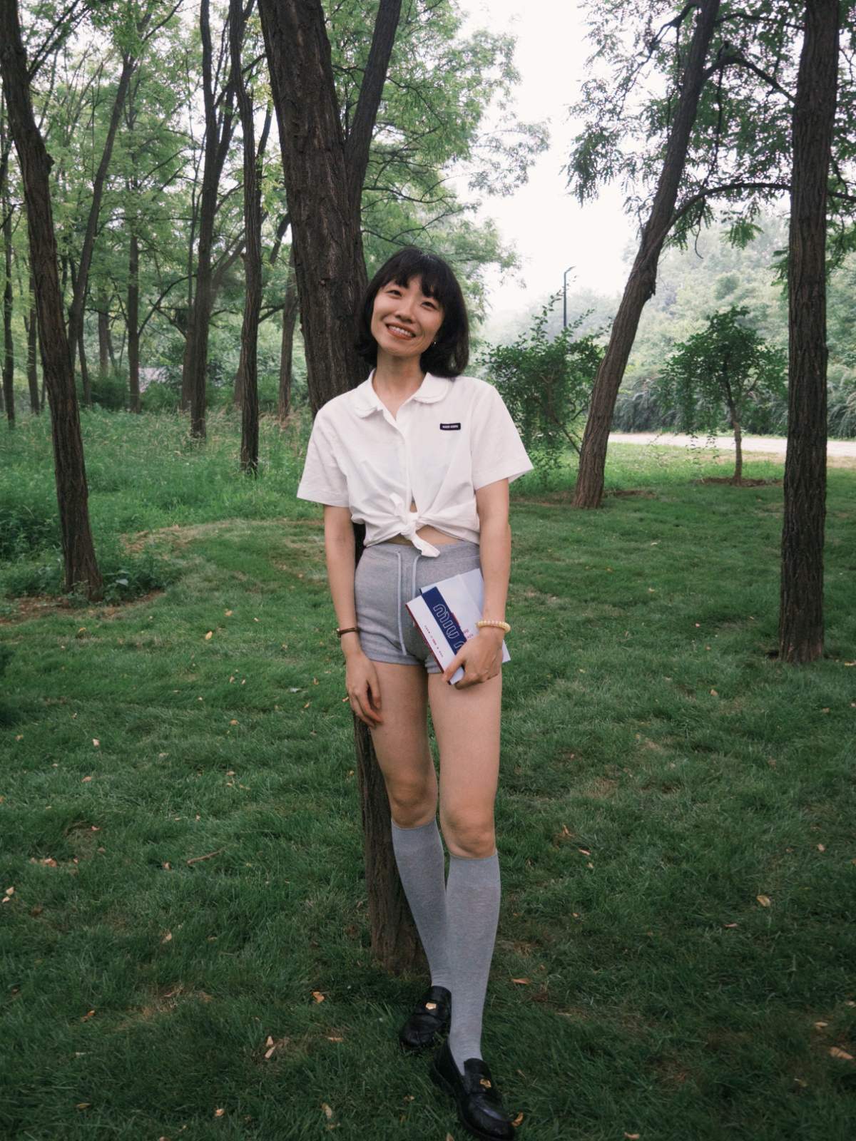 Miu Miu Summer Reads. Girl in white shirt & high-waisted shorts