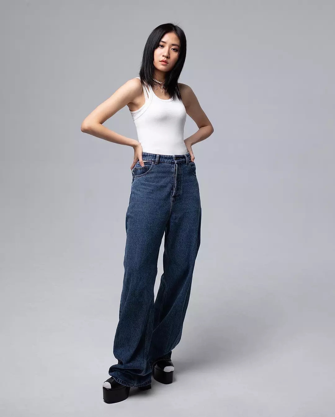 A girl with simple white tank top and wide-leg jeans