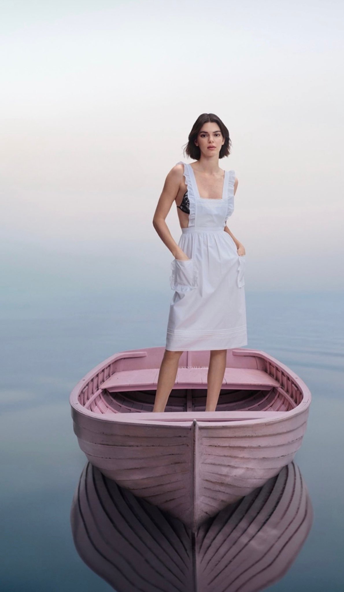 Kendall Jenner in a maid outfit standing on a boat