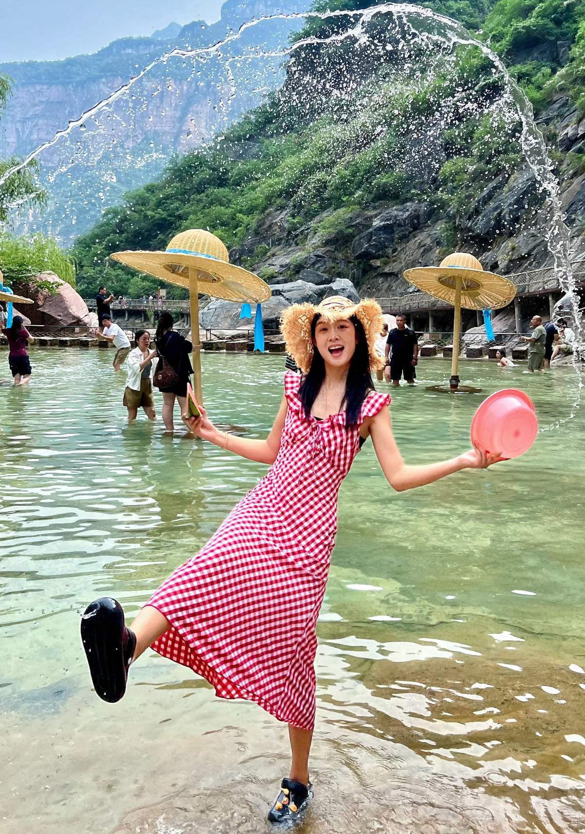 A lively girl wearing a Gingham dress is playing in the water