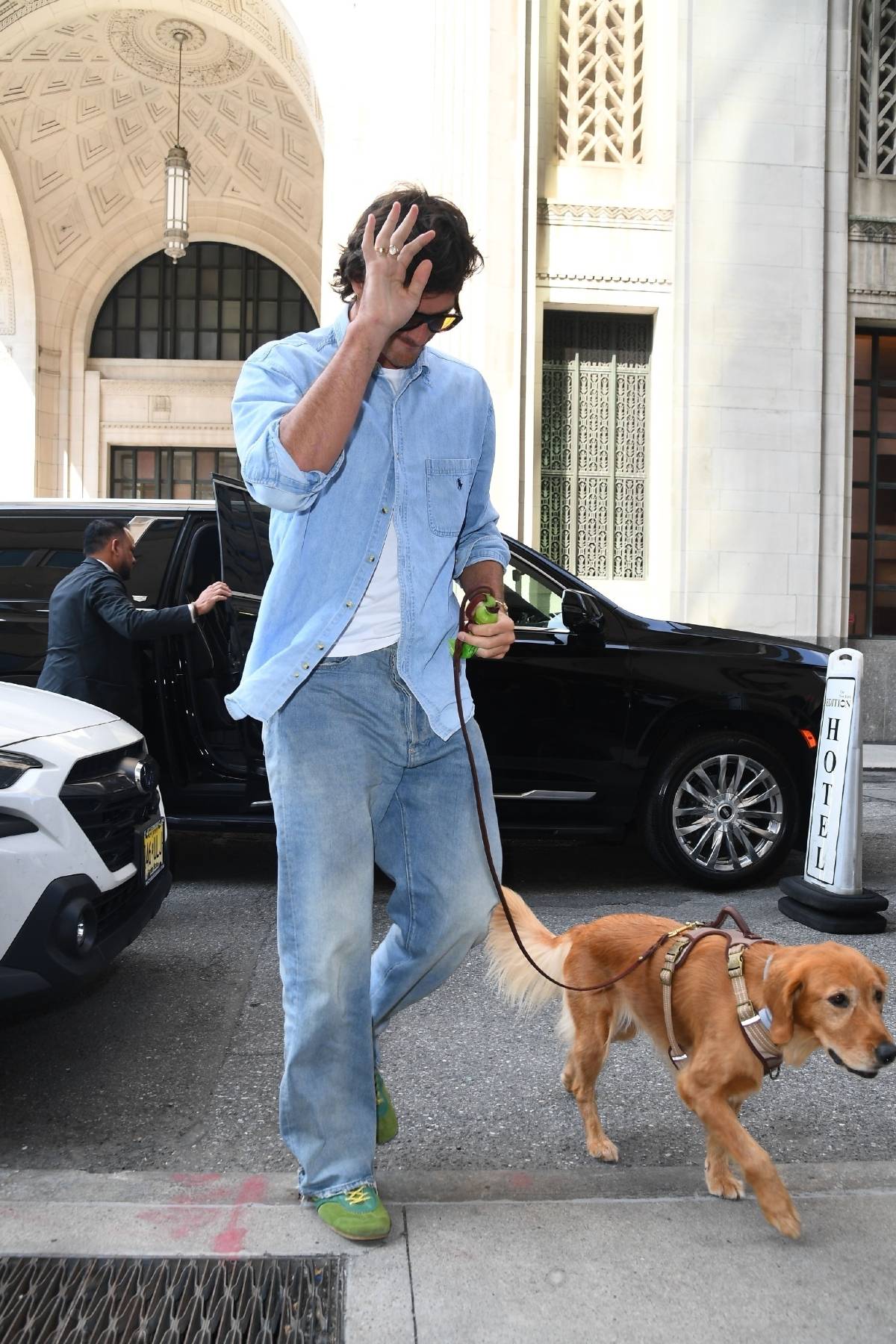 Which male celebrity is walking his dog, wearing jeans and green sneakers
