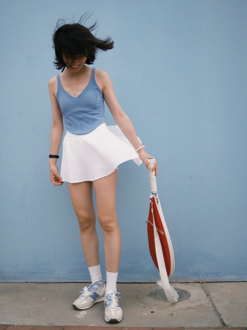 Classic tennis outfit: blue tank top paired with white pleated skirt