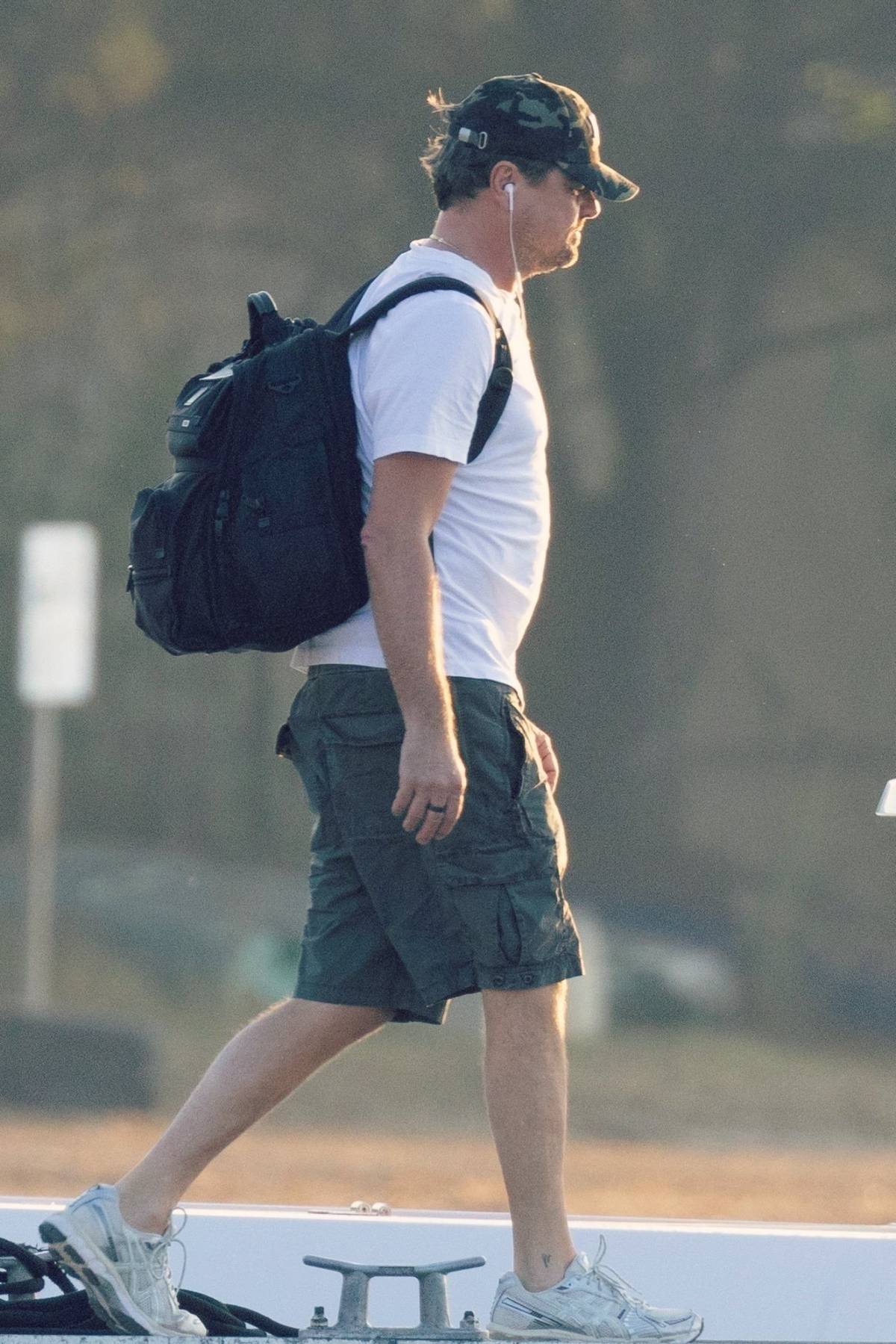Leonardo Dicaprio in a white T-shirt, cargo shorts and a heavy travel bag