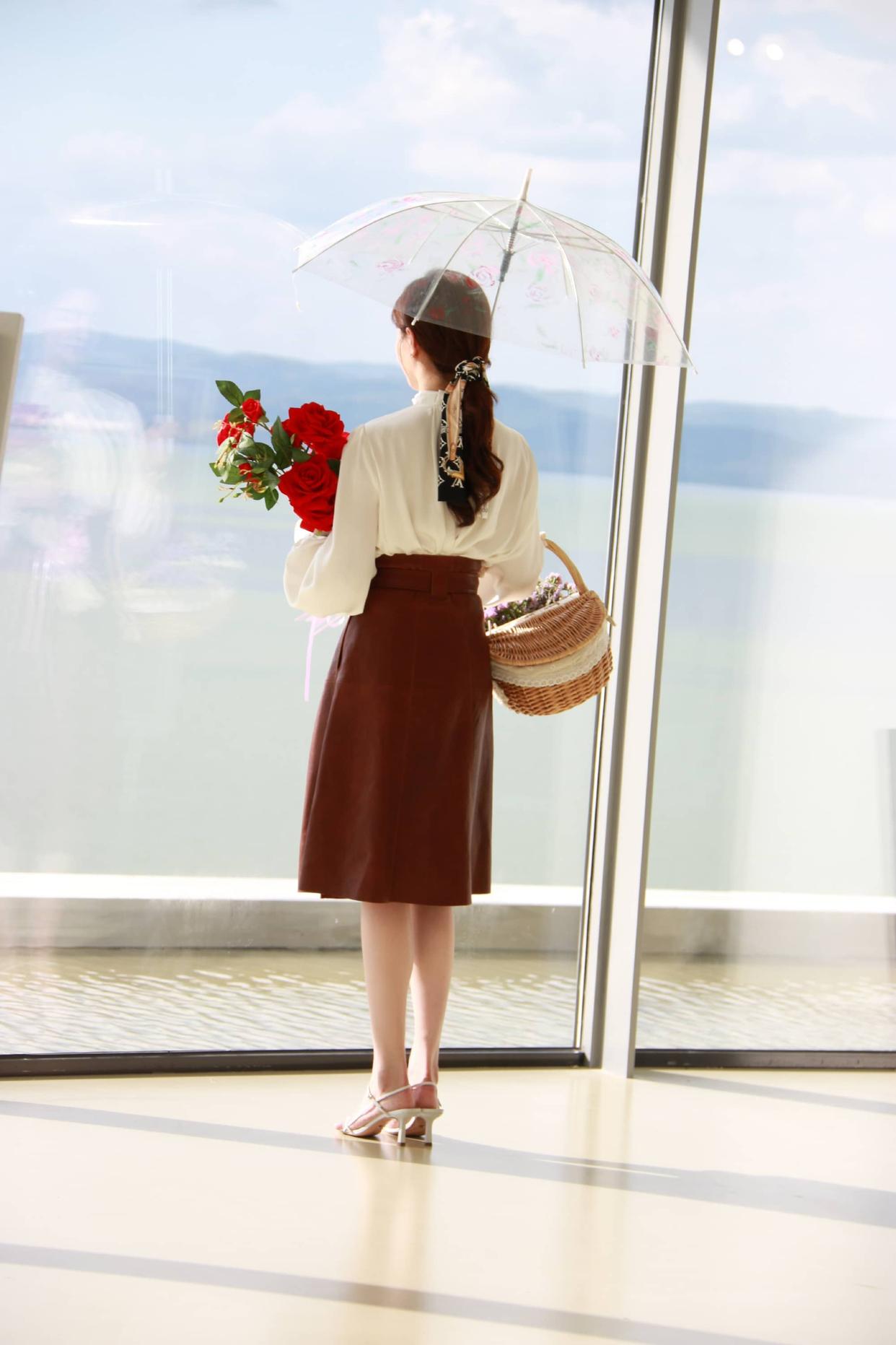 A long-sleeved off-white blouse tucked into a brown midi skirt — a very ladylike outfit.