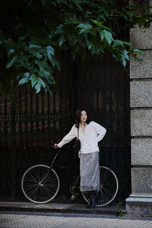 Elegant Combination of Ivory Blouse with Textured Skirt and Knee-high Boots for a Modern Street Style