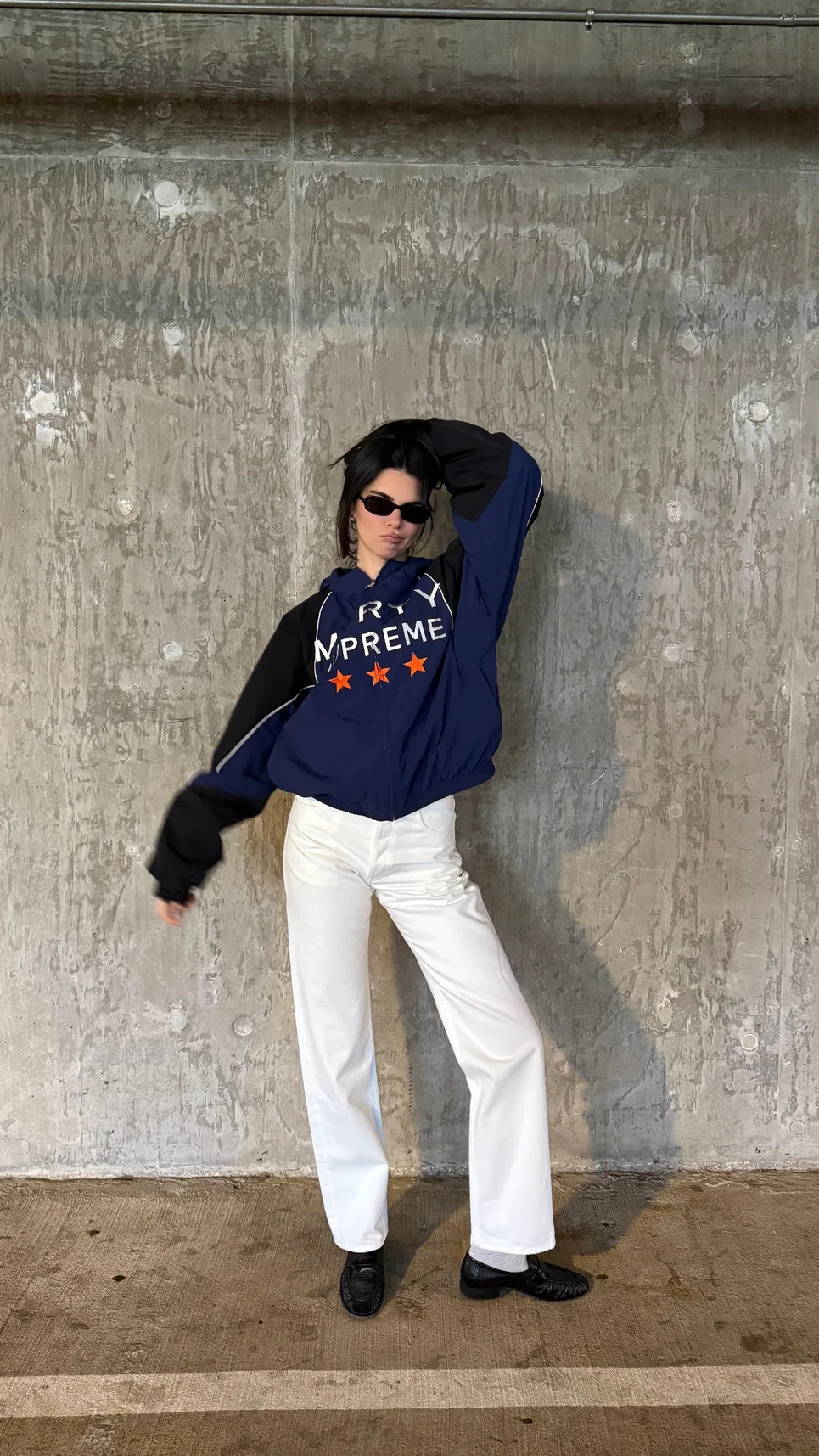 Kendall Jenner OOTD. Streetwear Style with Bold Logo Jacket and Elegant White Pants