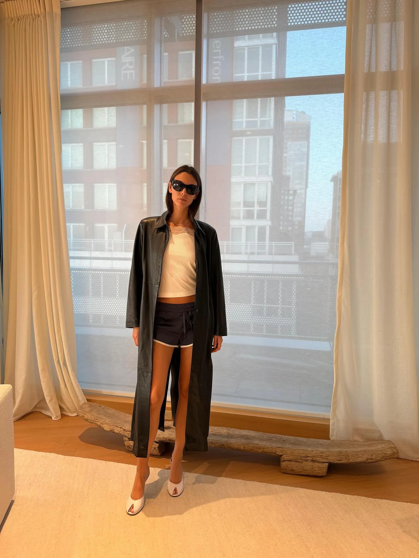 Vittoria Ceretti OOTD. Sleek Dark Coat with Casual Shorts and White Accents for Urban Chic Look