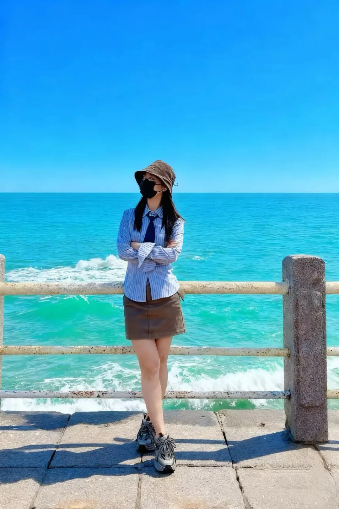 Casual Chic: Striped Shirt and Brown Skirt Ensemble with Bucket Hat for Seaside Adventure