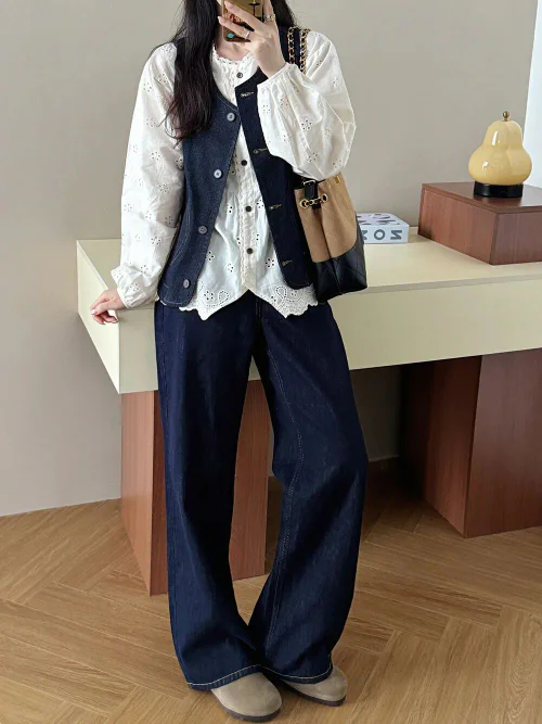 Effortless Chic: White Eyelet Blouse with Navy Vest and Wide-Leg Jeans