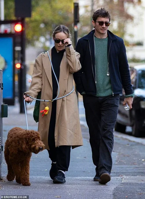 Celebrity couple street shots. Minimalist Chic: Camel Coat and Black Ensemble with Green Accent Bag