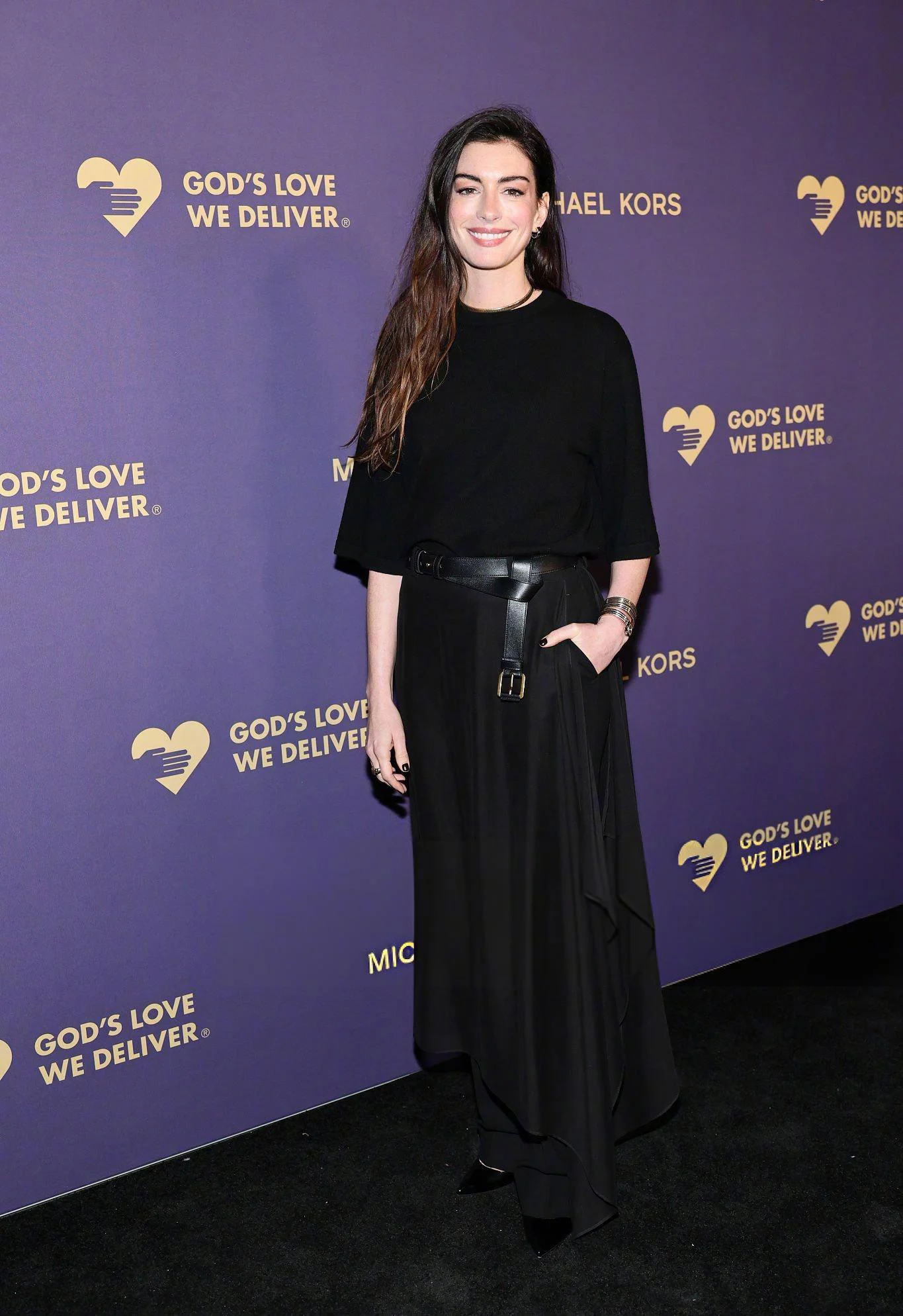 Anne Hathaway in Elegant Monochromatic Black Ensemble with Bold Belt and Flowing Skirt