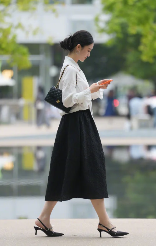 Early Autumn Street Style: Elegant Black and White Ensemble Featuring Tailored Blouse and Textured Midi Skirt