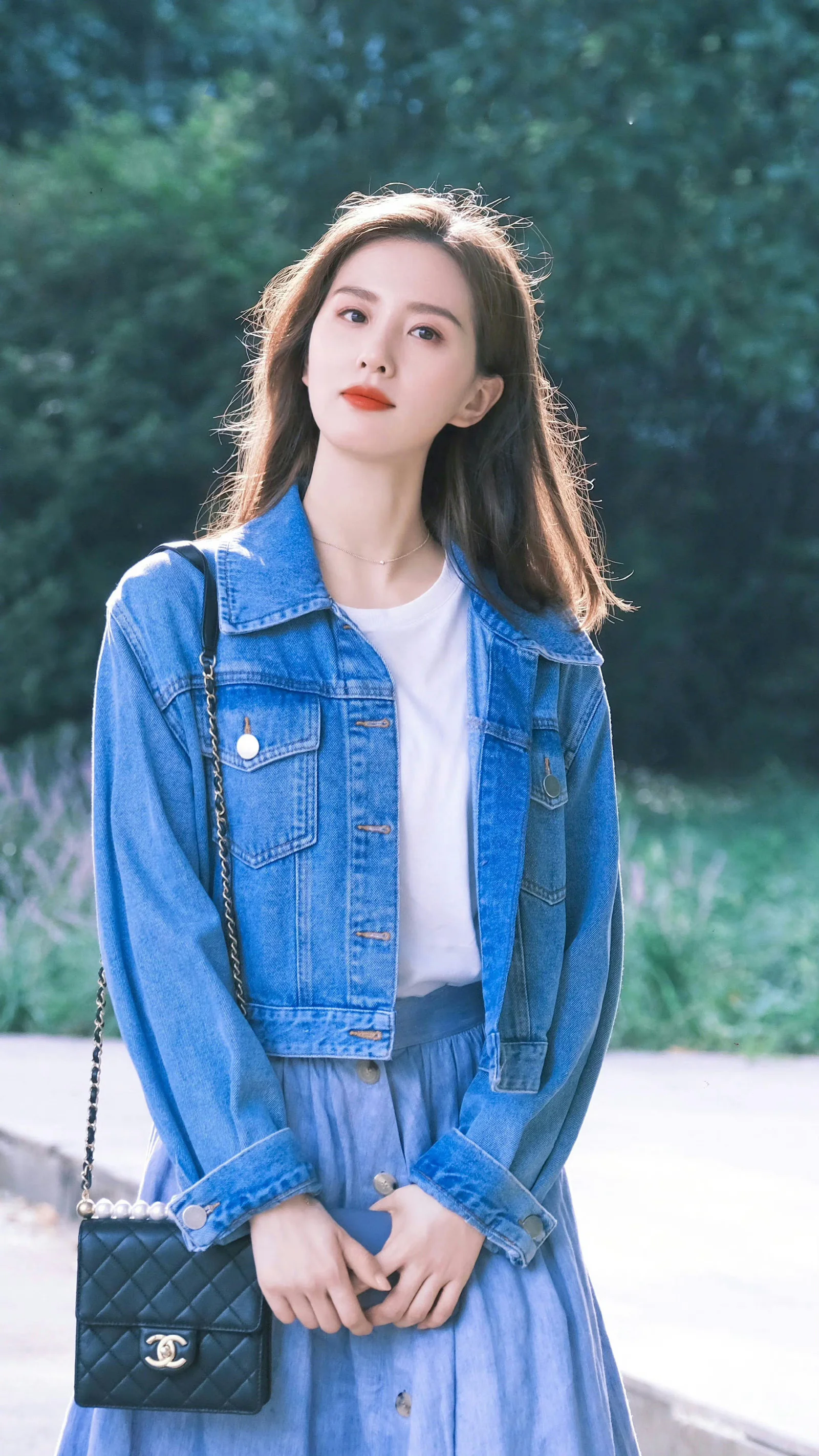 Casual Chic: Cropped Denim Jacket with Light Blue Skirt and Quilted Handbag