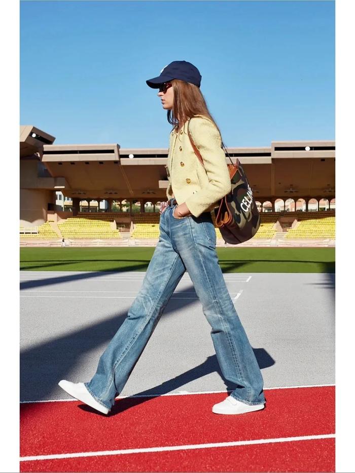 Chanel model street style: hat, jacket, backpack, jeans, and white sneakers.